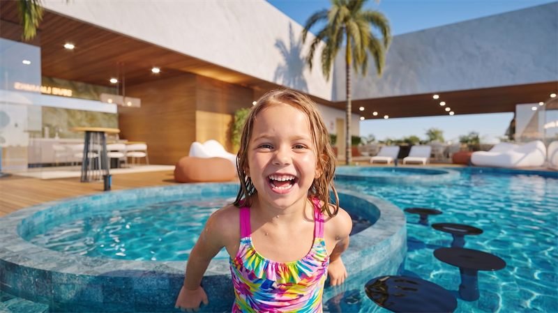 Imagem 3D humanizada com criança sorrindo na piscina da área de lazer