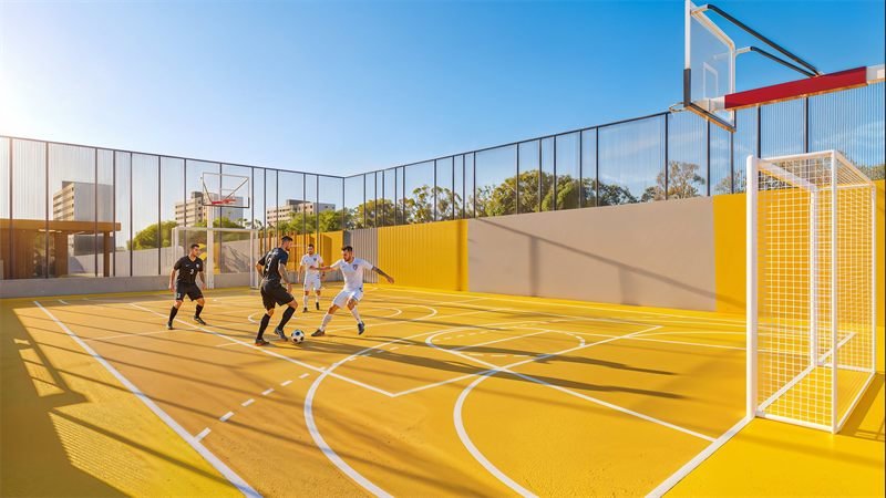 Imagem 3D humanizada da quadra poliesportiva amarela, com jogadores de futsal e tabelas de basquete